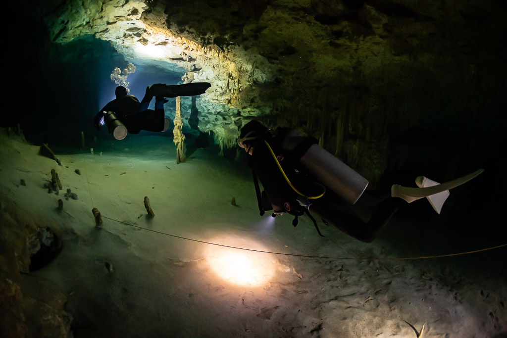 Two divers along the guideline, backmount diver lighting the sand, Quintana Roo, Mexico