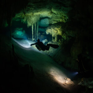 Diver silhouette in a narrow corridor between stalactite columns, Quintana Roo, Mexico
