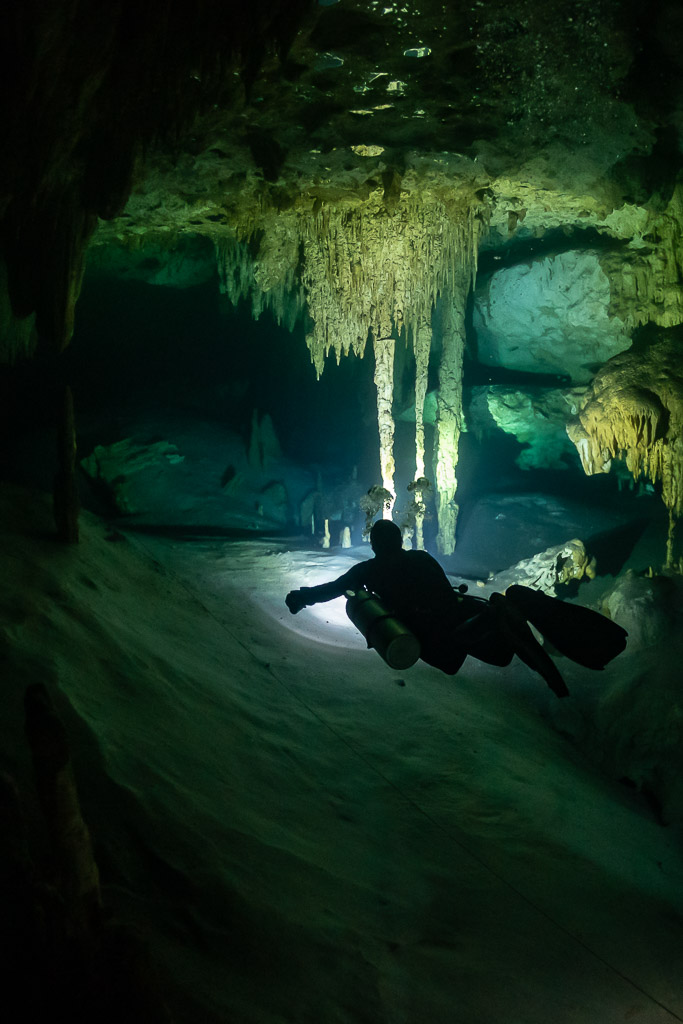 Vertical view of a diver passing between stalactite columns, Quintana Roo, Mexico
