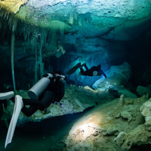 Diver in the foreground with white fins, second diver among columns, Quintana Roo, Mexico