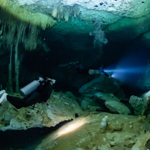 Two divers lighting a passage among columns under the cavern ceiling, Quintana Roo, Mexico