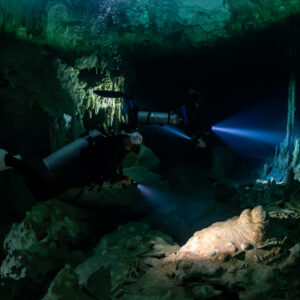 Two divers with torches pointing at white stalactites in a cavern, Quintana Roo, Mexico