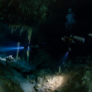 Two divers lighting a cavern room with bubbles near the ceiling, Quintana Roo, Mexico