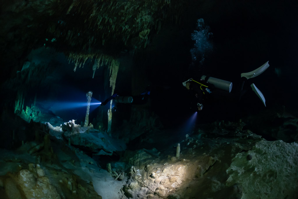 Two divers lighting a cavern room with bubbles near the ceiling, Quintana Roo, Mexico