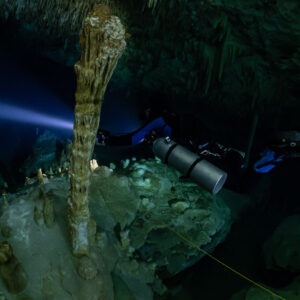Sidemount diver passing a pair of tall columns, guideline below, Quintana Roo, Mexico