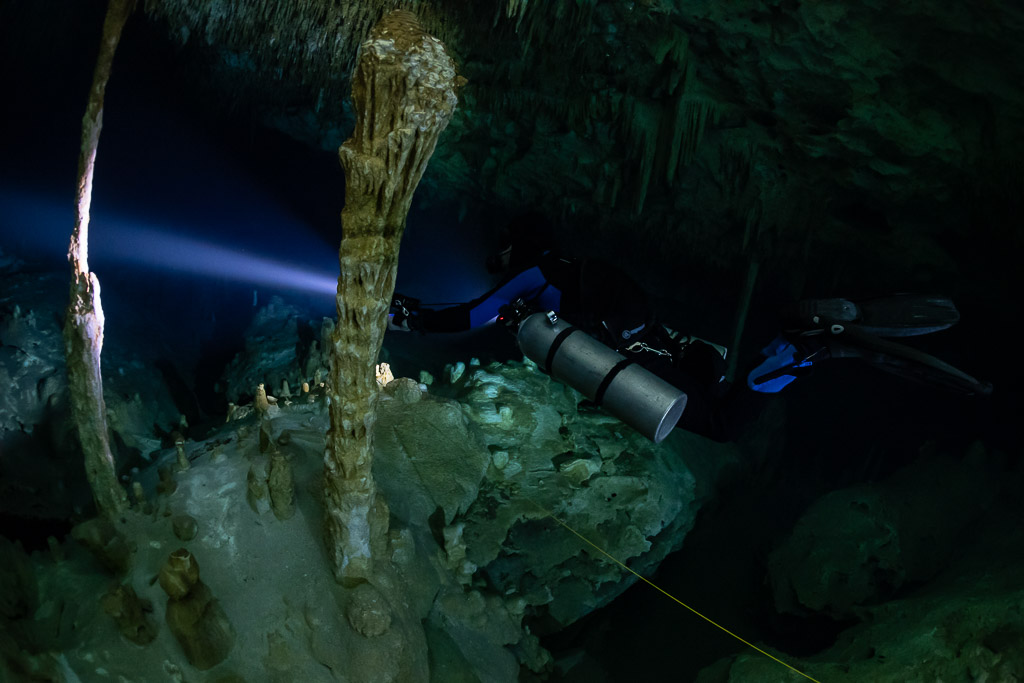 Sidemount diver passing a pair of tall columns, guideline below, Quintana Roo, Mexico