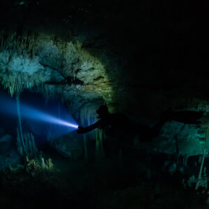 Sidemount diver lighting delicate stalactites in a dark chamber, Quintana Roo, Mexico