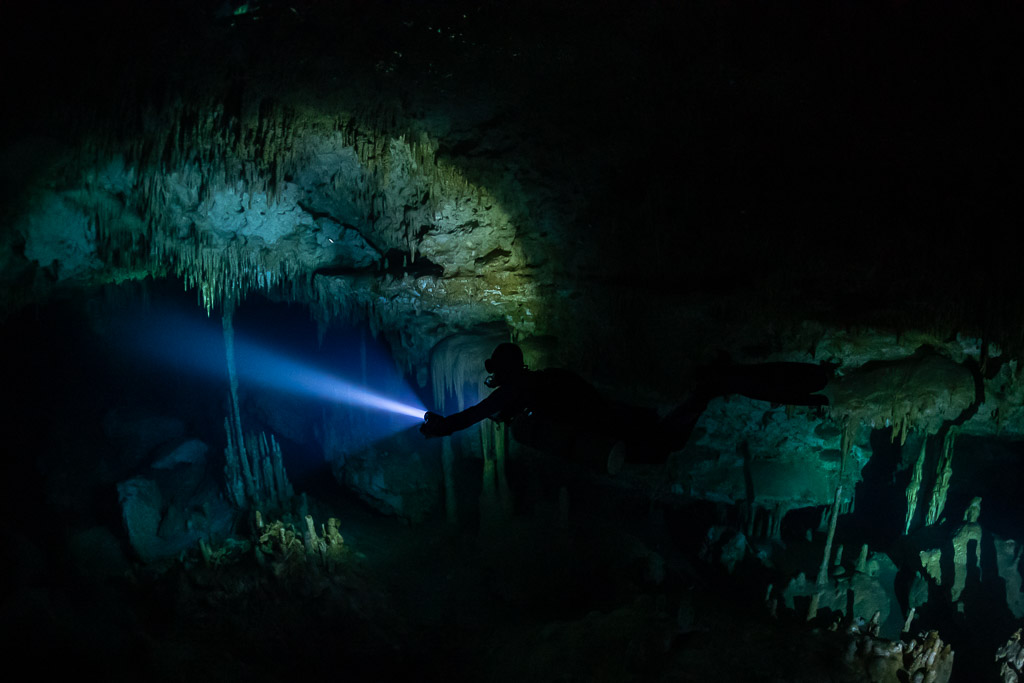 Sidemount diver lighting delicate stalactites in a dark chamber, Quintana Roo, Mexico