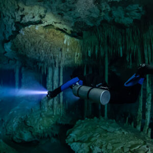 Sidemount diver with blue fins under a decorated ceiling, torch beam, Quintana Roo, Mexico