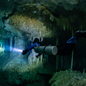 Sidemount diver near the camera lighting columns and stalactites, Quintana Roo, Mexico