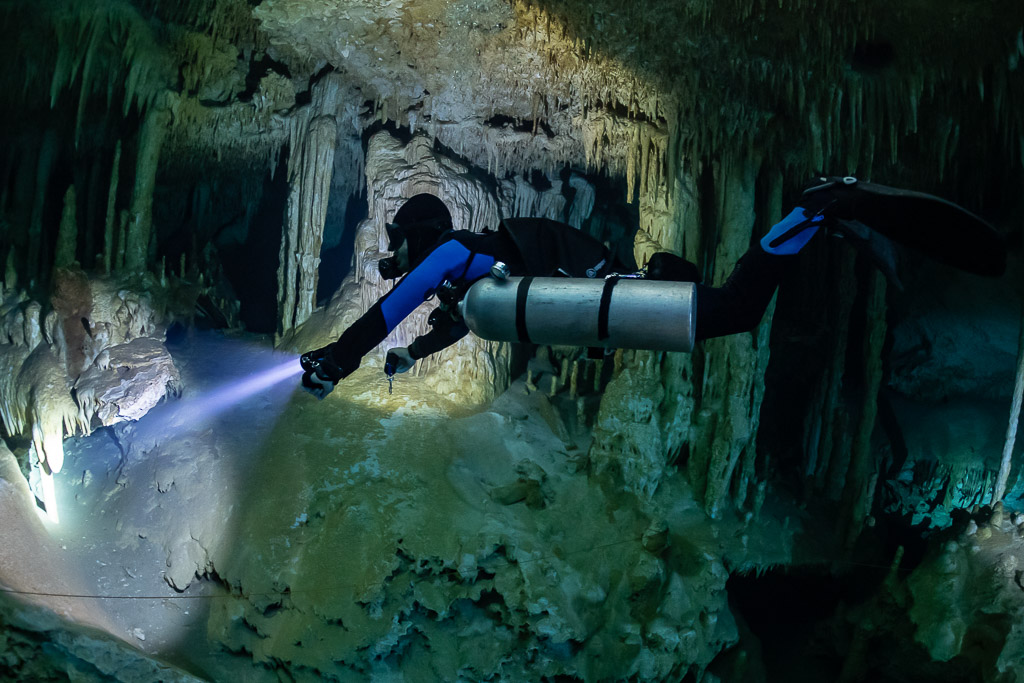 Sidemount diver close up lighting a white decorated cave wall, Quintana Roo, Mexico