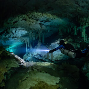 Sidemount diver lighting a turquoise gallery beneath stalactites, Quintana Roo, Mexico