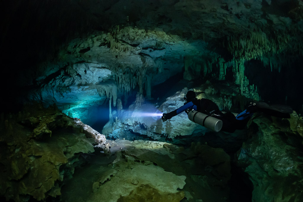 Sidemount diver lighting a turquoise gallery beneath stalactites, Quintana Roo, Mexico