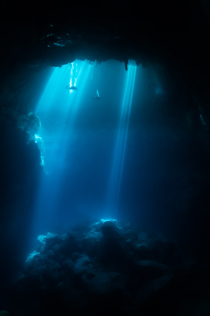 Vue verticale de rayons de soleil plongeant dans un cénote bleu profond, sans plongeur, Quintana Roo, Mexique