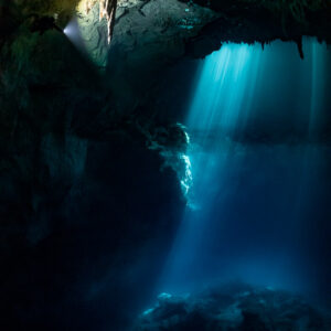 Cenote light shafts with a diver's torch beam near the cavern ceiling, Quintana Roo, Mexico