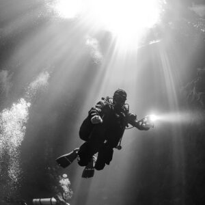Black and white cave diver silhouetted against a burst of sunlight, Quintana Roo, Mexico