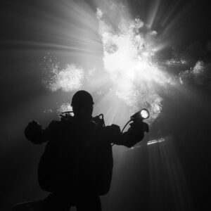 Black and white diver silhouette from below against a radiant cenote opening, Quintana Roo, Mexico