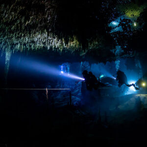 Team of cave divers with torches crossing a dark chamber along a guideline, Quintana Roo, Mexico