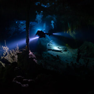 Cave diver sweeping a torch beam among columns and stalagmites, Quintana Roo, Mexico
