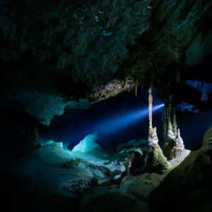 Torch beam illuminating slender stalagmites in a dark flooded cave, Quintana Roo, Mexico