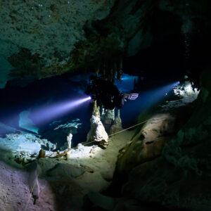 Cave diver pointing his torch past a stalagmite along the guideline, Quintana Roo, Mexico