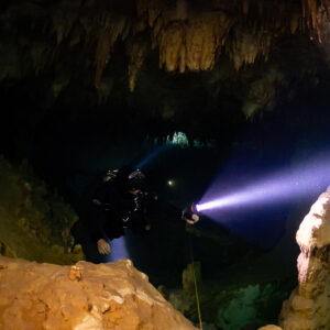 Cave diver's violet torch beam crossing a chamber of ochre formations, Quintana Roo, Mexico