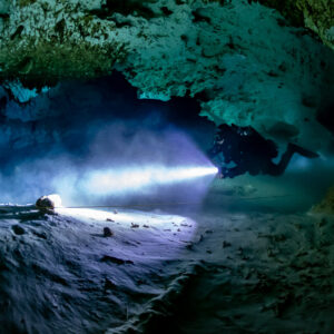Cave diver's torch beam cutting through a haze over a pale cave floor, Quintana Roo, Mexico