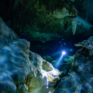Cave diver light glowing through a narrow gap between sculpted rock, Quintana Roo, Mexico