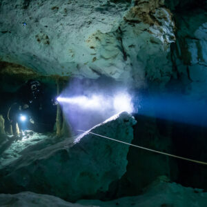 Cave diver's intense torch beam beside a guideline and limestone wall, Quintana Roo, Mexico