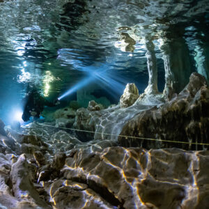 Two cave divers lighting a passage under a shimmering reflective ceiling, Quintana Roo, Mexico