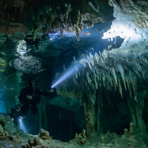 Cave diver beneath dense stalactite curtains near an air pocket, Quintana Roo, Mexico
