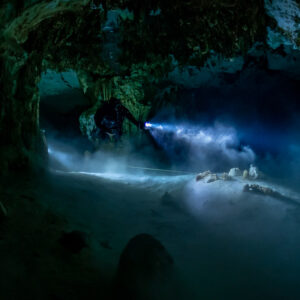 Cave diver torch revealing a halocline haze over the cave floor, Quintana Roo, Mexico