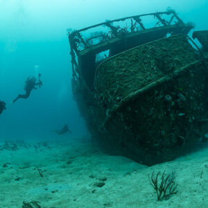 Divers approaching a sunken boat wreck resting on white sand, Playa del Carmen, Quintana Roo, Mexico