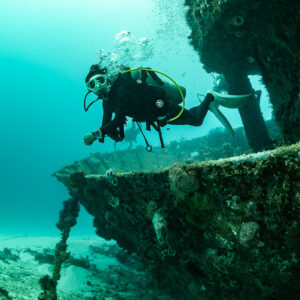 Woman diver posing on the bow of a sunken boat wreck, Playa del Carmen, Quintana Roo, Mexico