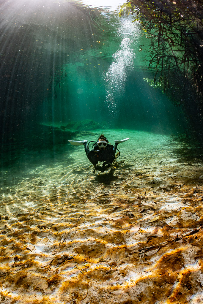Plongeur au-dessus de rides de sable sous une colonne de bulles, format vertical, Casa Cenote, Quintana Roo, Mexique