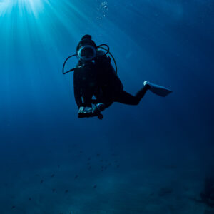 Diver at safety stop under a sunburst, vertical frame, Cabo Pulmo, Baja California Sur, Mexico