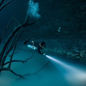Diver above the sulfide layer with torch beam and bubbles, vertical frame, Cenote Angelita, Quintana Roo, Mexico