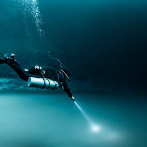 Sidemount diver close-up pointing torch into the sulfide cloud, Cenote Angelita, Quintana Roo, Mexico