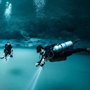 Sidemount diver and companion above the cloud, torch beams downward, Cenote Angelita, Quintana Roo, Mexico