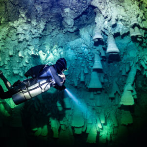 Sidemount diver lighting rows of bell formations in green light, Cenote El Zapote, Quintana Roo, Mexico