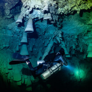 Diver under a large bell formation in a circle of light, Cenote El Zapote, Quintana Roo, Mexico