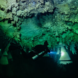 Diver lighting a single large bell formation from below, Cenote El Zapote, Quintana Roo, Mexico
