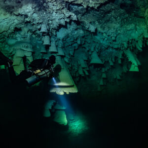 Diver in the dark with torch beam among bell formations, Cenote El Zapote, Quintana Roo, Mexico