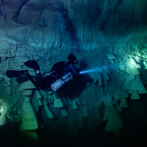 Sidemount diver between two lit groups of bell formations, Cenote El Zapote, Quintana Roo, Mexico