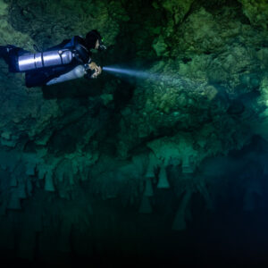 Sidemount diver seen from above beaming along a dark cenote wall, Cenote El Zapote, Quintana Roo, Mexico