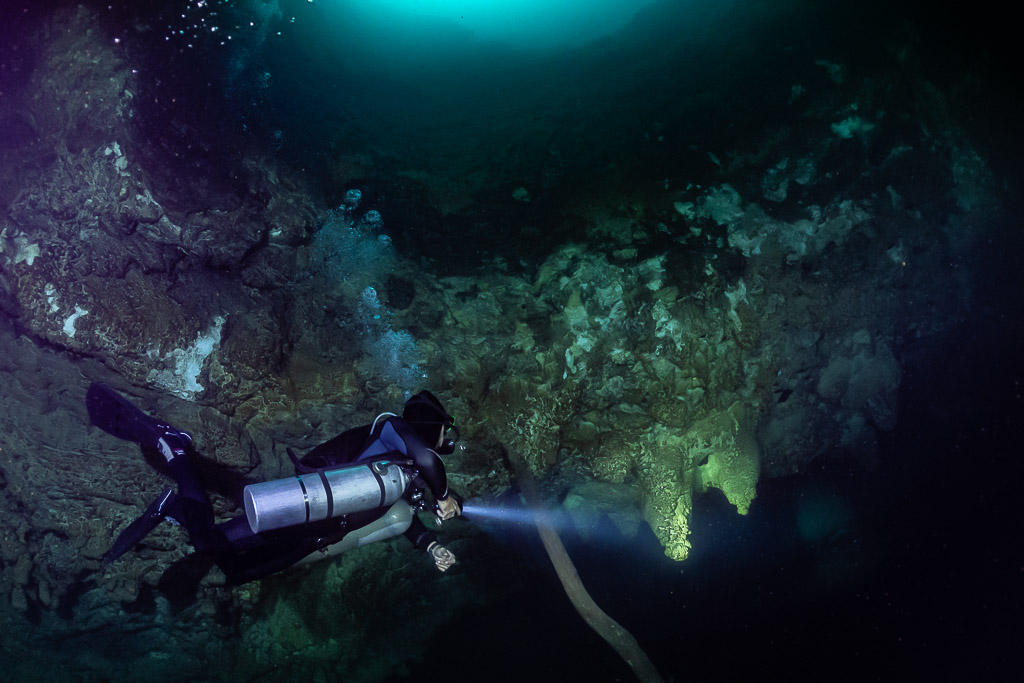 Plongeur en sidemount sous l’ouverture du cénote baignée de lumière turquoise, cénote El Zapote, Quintana Roo, Mexique