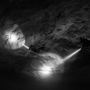 Black and white two divers lighting circles on a cavern wall, Quintana Roo, Mexico