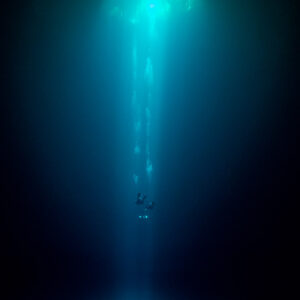 Column of light falling from a small cenote opening into darkness, Quintana Roo, Mexico