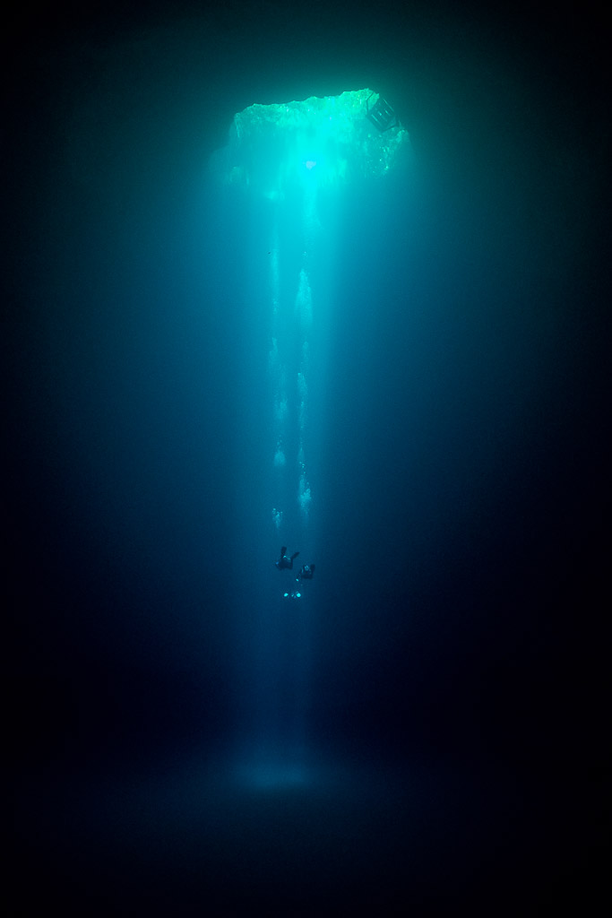 Colonne de lumière tombant d’une petite ouverture de cénote dans l’obscurité, Quintana Roo, Mexique