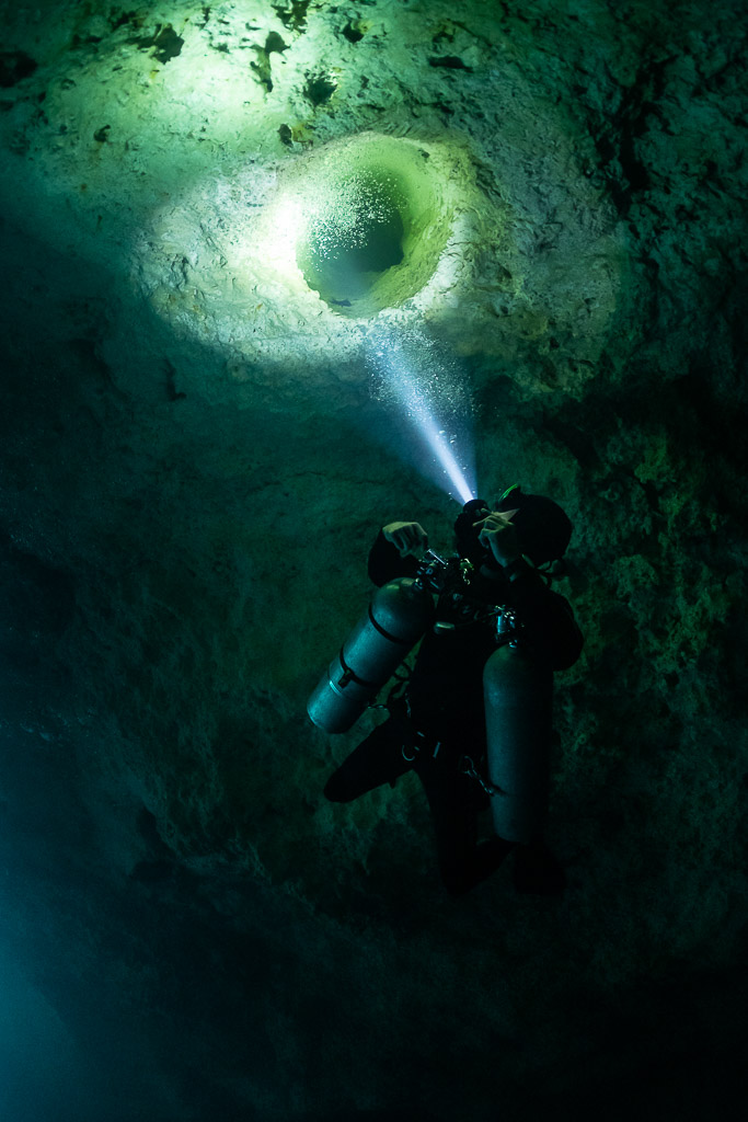 Plongeur éclairant un trou rond du plafond rempli de ses bulles, Quintana Roo, Mexique